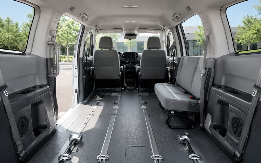 The clean interior of a medical transport van showing seating and floor securement tracks.